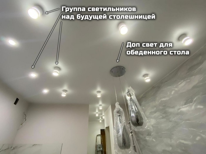Натяжной потолок на кухне: накладные и встроенные светильники подсвечивают рабочую зону, светильники на подвесах подсвечивают обеденный стол – Фото 2